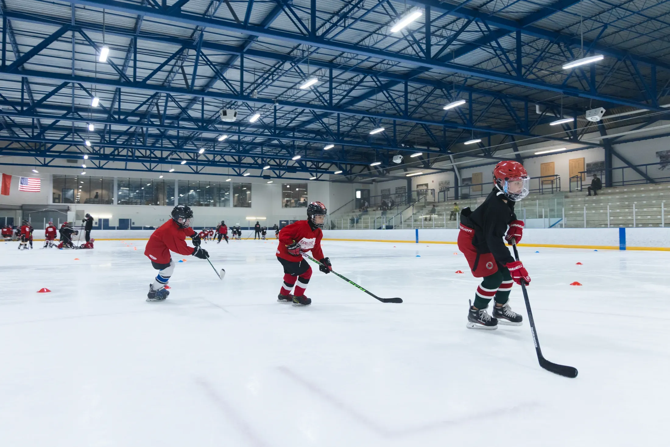 A wide line of Edge players moving across the ice in formation — the same drill, repeated until it sticks